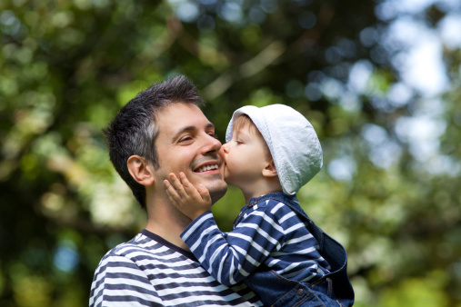 Image of a child kissing a father on a cheek, shallow depth of field