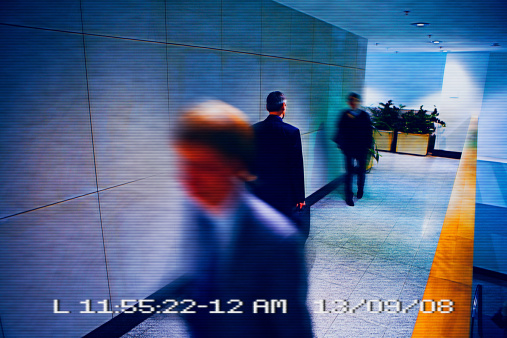Businessmen walking in a corridor viewed from a surveillance camera