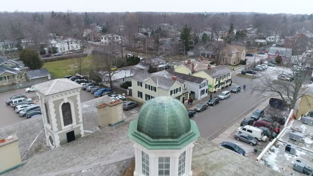 A drone captures an aerial view of Niagara-on-the-Lake's downtown courthouse, passing over the tower on the roof, capturing the surrounding historical buildings.