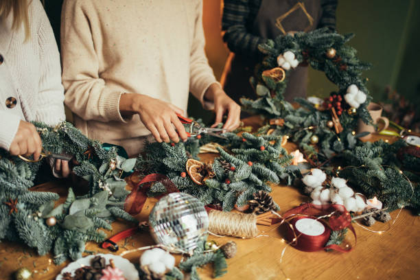 istock Happy women making Christmas wreath using natural pine branches and festive decorations. 1836327359
