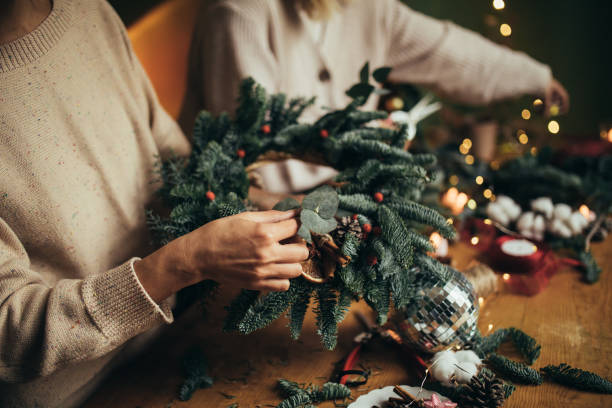 istock Happy women making Christmas wreath using natural pine branches and festive decorations. 1836327464