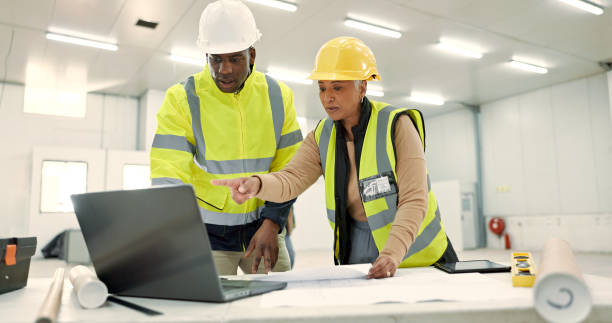istock Engineering people, teamwork and laptop for construction site planning, floor plan and building design in warehouse. Industry man and senior woman with computer for architecture or blueprint solution 1836331029