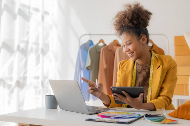 istock Young African woman selling clothes in streaming video Start a small SME using your smartphone or tablet to receive name orders and ready to ship packages. 1836333637