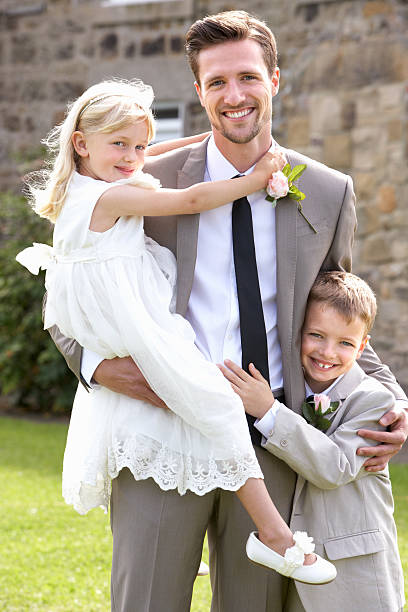 Groom With Bridesmaid And Page Boy At Wedding Smiling To Camera