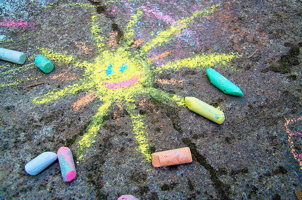 Colorful sun drawn on asphalt with sidewalk chalk stock photo