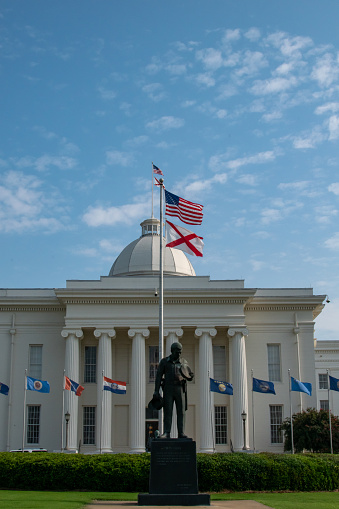 Montgomery Alabama State Capitol building with ionic columns, Dome, flags,  Duty Called statue, and beautiful landscaping\n\n\