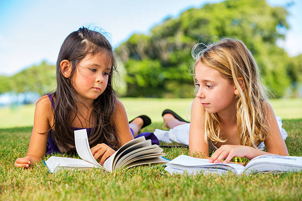 istock Little Girls Reading Books on Grass 183636097