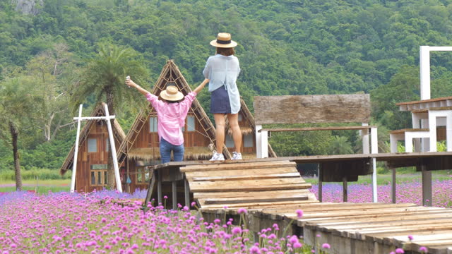 Woman takes photos for his mother in a pink flowers field in summer.