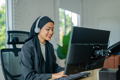 confident muslim woman working with computer and headset in call center as customer support representative