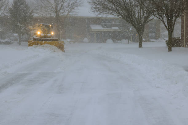 an ice plough removes snow from parking lot during a heavy snowfall snowstorm - snowplow snow parking lot pick up truck imagens e fotografias de stock