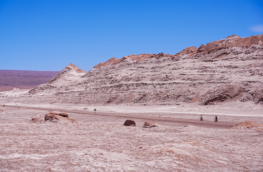 Couple riding bicycles on high road in Atacama Desert, northern Chile, South America