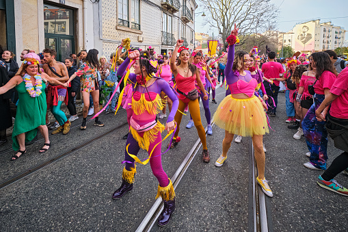 Maastricht, Limburg, Netherlands, february 10th 2013, a group of cheerful men and women wearing yellow/red/green ceremonial make-up and costumes walking along in the sunday carnaval parade on the famous 13th century 'Sint Servaasbrug' over the Meuse river in Maastricht (the oldest bridge in the Netherlands) - people are standing side by side on both sides of the road to watch the parade - with over 3 million annual visitors the city is a popular travel destination