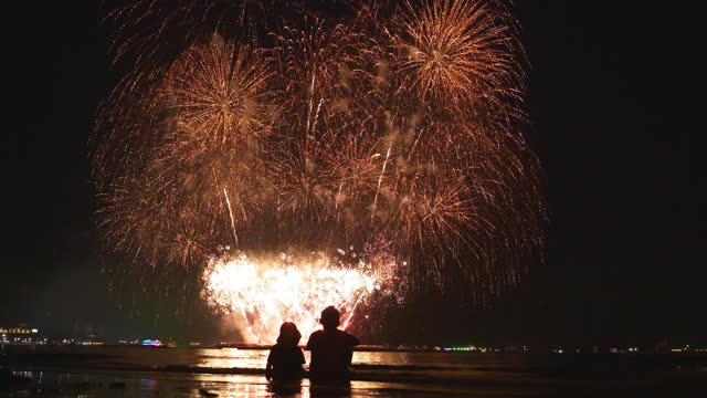 Two kids watch fireworks with different competitions between plenty of countries and different of design fireworks.
