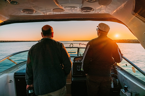 Mature Man with a Local Sailing Tour Guide navigating a Speed Boat in California at Sunset