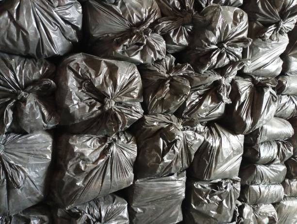 istock Many filled black garbage bags neatly stacked in a row. 1836554163