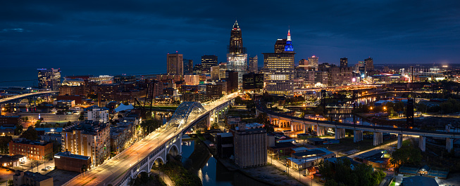 Panoramic drone shot of the downtown skyline from across the Cuyahoga River in Cleveland, Ohio at night. \n\nAuthorization was obtained from the FAA for this operation in restricted airspace.