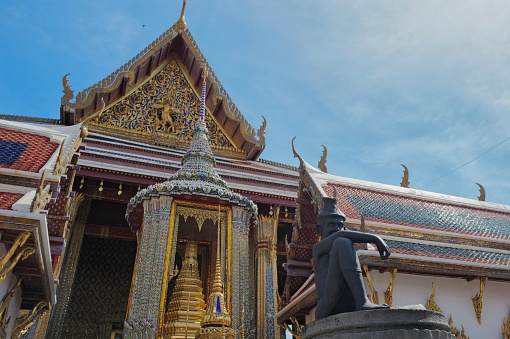 Emerald's buddha Chapel with Statue of seated Hermit  with Gold chapel background with small gold stupa behind