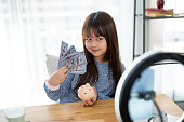 A cute young Asian girl kid influencer is sharing her money saving tips on her social media.