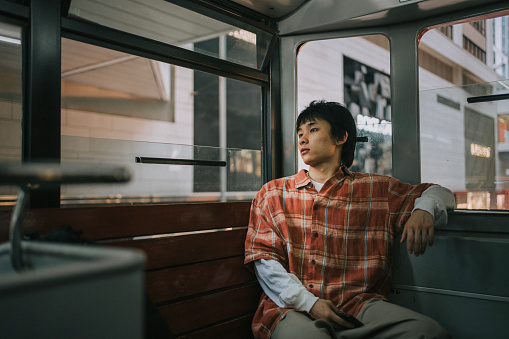 Asian Chinese young man sitting in double-decker bus in Hong Kong Island alone