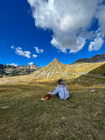 Girl with dreadlocks enjoying mountain views with her dog.