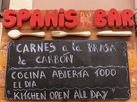 Low angle view of blackboard with list of dishes offered in Spanish bar