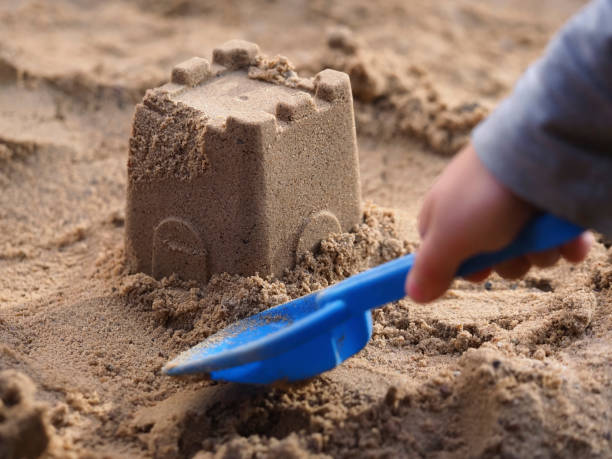 kid is building a castle in the sandbox stock photo