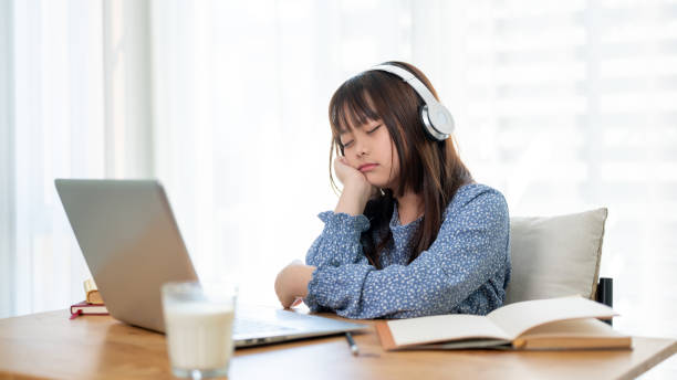 istock A cute young Asian girl is falling asleep while studying online at a table in her room. 1836776643