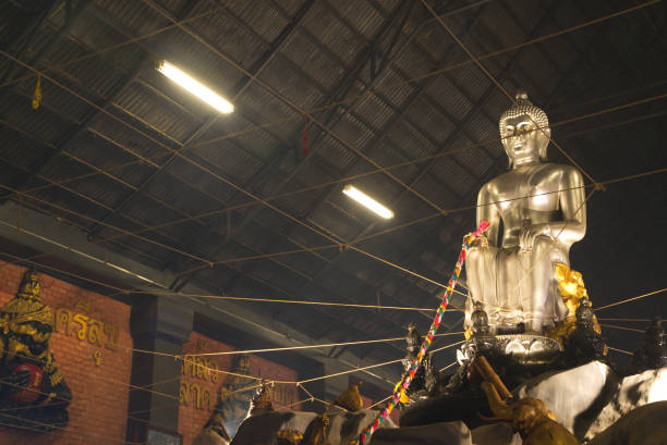 A large silver seated Buddha statue in the Pa Lelai pose. Inside the sermon hall At the bottom, devotees can walk under it. For good fortune at Wat Tha Mai temple. Located at Samut Sakhon Province in Thailand.