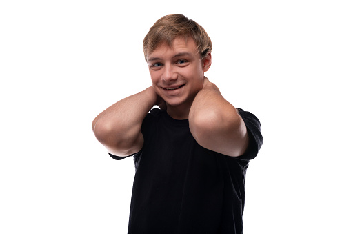 European blond teenager boy wearing a black T-shirt is confident in himself.