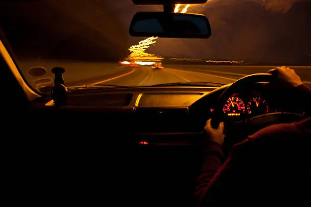 A point of view (POV) from a passenger of a car as it speeds down the motorway.  The lights rushing past, at night.