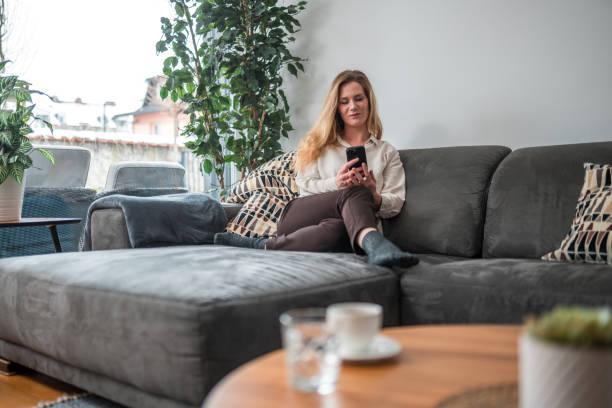 istock Mid Adult Caucasian Female Using Smartphone on Sofa 1836854854