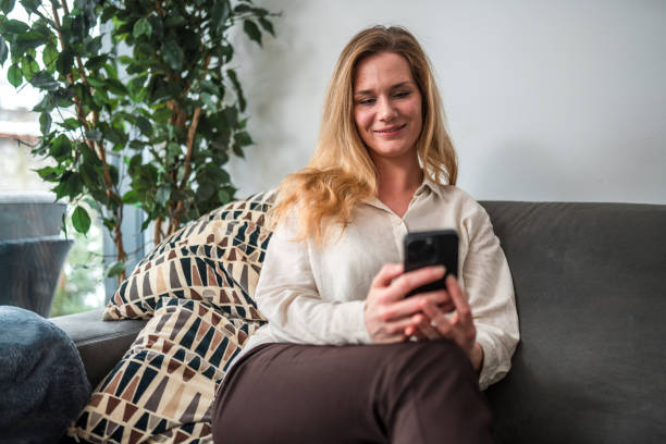 istock Mid Adult Caucasian Female Using Smartphone on Sofa 1836854941