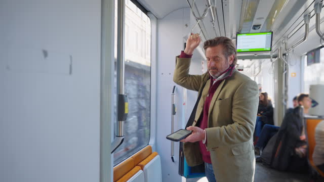 SLO MO Mature Businessman Holding Hanging Strap and Using Smartphone While Traveling in Train