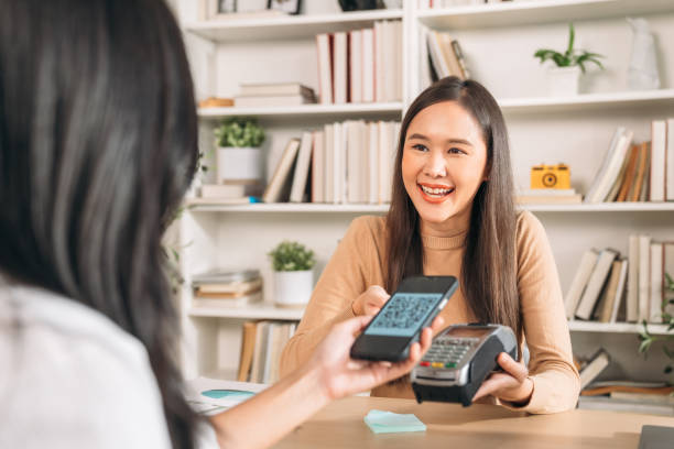 une femme yong tient un smartphone pour le paiement au magasin. femme utilisant la technologie pour le transfert d’argent. - pay phone telephone people women photos et images de collection