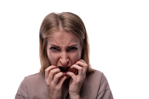 Young woman making a scared face expression over isolated gray background, studio shot. Image taken with Hasselblad H3D camera system and developed from camera RAW.