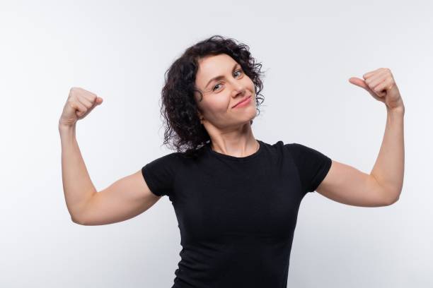 istock Caucasian woman with black curls shows her strong muscles 1836909866