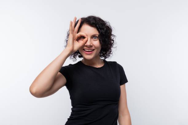 Adult curly European woman in a black T-shirt smiling cutely and grimacing Adult curly European woman in a black T-shirt smiling cutely and grimacing. cutely stock pictures, royalty-free photos & images