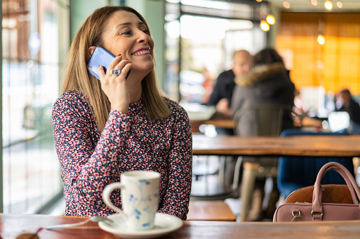 Young Woman In A Coffee Shop Talking On Mobile Phone