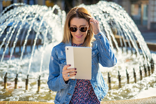 Happy And Smiling Woman Using Tablet PC In The Park