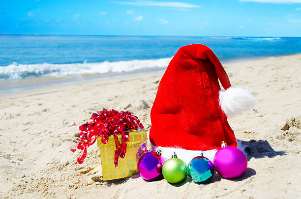istock Christmas hat with gift box and balls on the beach 183692477