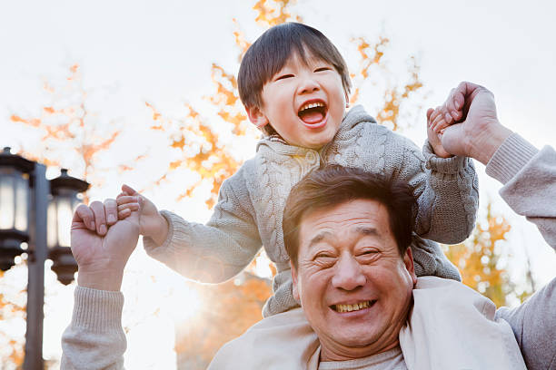 A grandfather with his grandson on his shoulders Grandfather Carrying Grandson on His Shoulders china chinese ethnicity smiling grandparent stock pictures, royalty-free photos & images