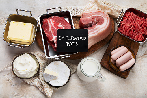 Saturated fats on tables. Raw meat, sausages, cheese, butter. Bad food concept. Top view