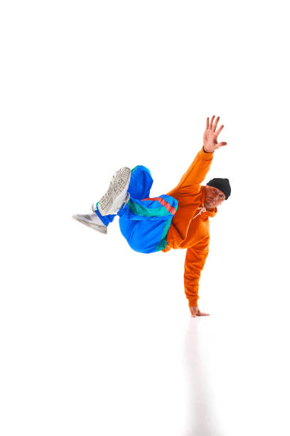 istock Young sportive man, dude wearing stylishly bright sport cloth dancing breakdance elements, freezes against white background. 1836940354
