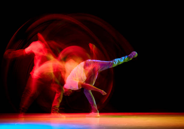 istock Young sportive guy dancing hip-hop, breakdance against black studio studio background in red neon light with motion blur. 1836940901