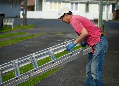 Man folding the ladder after finishing work. Home maintenance work. Auckland.