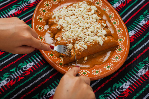 Person eating enchiladas with red pipian. Typical Mexican food.