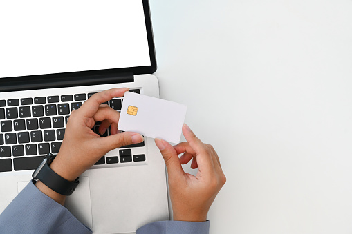 Above view of young woman holding credit card making purchase, payments on web stores via laptop