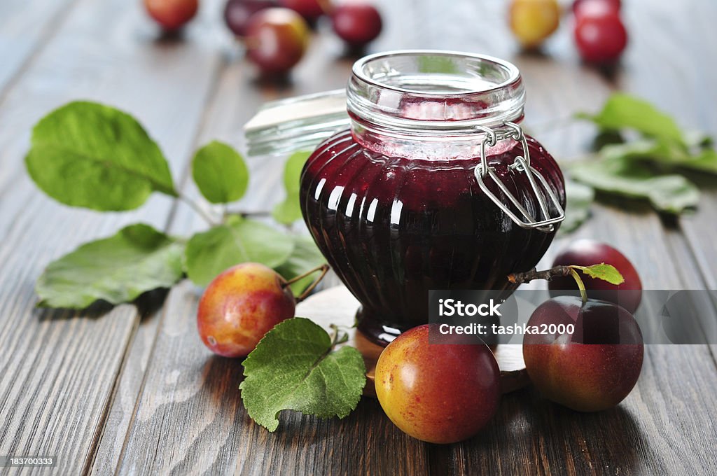 Plum jam Plum jam in a glass jar and fresh fruits with leaves on wooden background closeup Breakfast Stock Photo