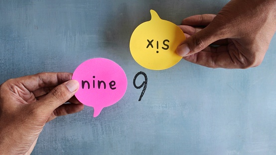 Hand holding speech bubble with text NINE and SIX.