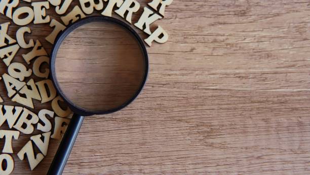 istock Magnifying glass with scattered alphabet letters on the table. 1837009999